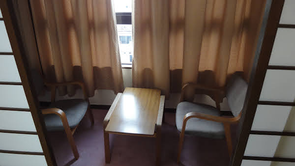 sliding doors lead to a small room with a table and two chairs and a curtained window
